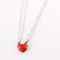 Close-up of red geometric magnetic heart pendants on silver chains for couples - Red
