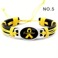 Detalle de pulsera de cuero trenzado amarillo y negro con símbolo de lazo amarillo - Fighter Amarillo (NO.5)