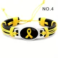Primer plano de pulsera de cuero negro tejida a mano con un medallón de lazo amarillo de conciencia - Cinta Amarilla (NO.4)