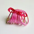 Set van tien felroze glitter jelly bangles van siliconen vastgeknoopt met een rood lint - Rozerood