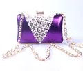 Detail view of purple evening clutch with pearls and crystal decorations on a gold chain. - Purple