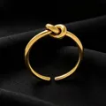 Close-up of elegant gold titanium steel love knot ring on black fabric background - Ring / Gold