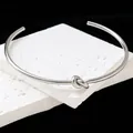Close-up of a minimalist silver titanium steel knot cuff bracelet on white stone - Bangle / Silver