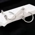 Close-up detail of minimalist titanium steel silver knot hoop earrings on white stone - Earrings / Silver