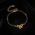 Vista detallada de una pulsera de acero de titanio dorada con un dije de lazo delicado - Pulsera / Dorado