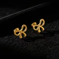 Primer plano detallado de pendientes de lazo en acero de titanio dorado sobre terciopelo - Pendientes de botón / Dorado
