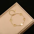 Detalle de pulsera de acero inoxidable dorado con elegantes dijes de flores de cinco pétalos - Doble cara en blanco y negro