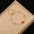 Primer plano de una pulsera de acero inoxidable dorada con flor roja de cinco pétalos - Negro y Rojo Doble Cara