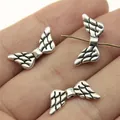 Vintage silver angel wing beads for jewelry making, displayed on a hand with threading. - Wing Shape (B13535) / Antique Silver