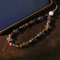 Handmade phone strap with tiger's eye beads and natural pearl on brown surface - Tiger Eye Natural Pearl Glass Phone Chain
