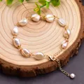 Detailed view of a handmade baroque pearl bracelet with gold wire wrapping on a wood base. - Adjustable Baroque Pearl Bracelet / Wire Wrapped Style / Gold/White