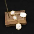 Handcrafted baroque pearl drop earrings with gold wire wrap on a wooden display - Gold Wire Wrapped Baroque Earrings / White Round Square Baroque Pearl