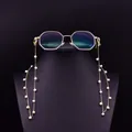 Detail of freshwater pearl eyeglass chain with golden octagonal sunglasses on black stand - Natural Freshwater Pearl Chain Style