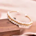 Elegant gold wire-wrapped bracelet with natural white pearls on champagne silk background. - Hand-Wrapped Pearl Bangle / White