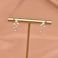 Elegant gold-plated dangling earrings featuring clusters of lustrous small white pearls. - Grape Stud Style