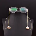 Elegant baroque pearl and shell eyewear chain in golden finish on black display stand - Natural Shell Pearl Pendant Eyeglass Chain