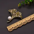 Elegant gold ginkgo leaf brooch with white pearl and crystals on dark background. - Ginkgo Leaf Brooch / White
