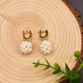 Dettaglio macro di orecchini a sfera in perle naturali su sfondo di legno rustico naturale - Sfera di Fiori Perle Strass a Clip