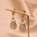 Vintage vergoldete Tropfenohrringe mit eleganten Barockperlen auf einem Display. - Tropfenförmige Perlenohrringe