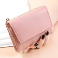 Close-up detail of a dusty pink pebble grain leather wallet with elegant double zippers - Pink