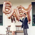 Large 40-inch rose gold BABY foil balloons held by a couple for party decor - Baby / 40 Inch / Rose Gold