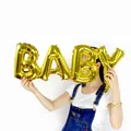 Primo piano di un palloncino in foglia d'oro con la scritta BABY per decorazioni feste - Oro