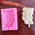 Detail view of a pink tiger-shaped silicone mold and a white chocolate lollipop result. - Tiger