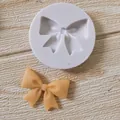 Detail of circular bow-shaped silicone mold with yellow fondant bow on textured wood. - Single Large Bowknot