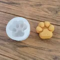 Primer plano de un molde de silicona de pata de gato blanco con una vela de cera amarilla - Pata de gato