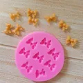Detail of pink silicone mold with 8 bow cavities and finished fondant bow pieces - 8-Cavity Round Bow