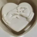 Détail d'un moule en silicone en forme de cœur avec relief de mains et une bague - Échange de Bagues