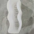 Macro detail view of wavy silicone mold interior with reversed BE KIND phrase engraving - BE KIND