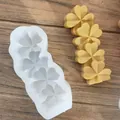 Moule trèfle en silicone blanc avec des pièces de cire jaune sur une surface en bois - Trèfle à Trois Cavités (1)