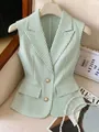 Dettaglio del blazer senza maniche a righe bianche e verdi con bottoni di perle. - Verde chiaro