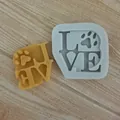 Close-up detail of LOVE silicone mold featuring a paw print design and wax sample. - Paw Love