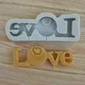 Detail view of Love heart silicone mold with finished yellow wax casting on wood - LOVE