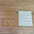 Detailed macro view of white silicone alphabet mold and orange chocolate letters - Uppercase Letters