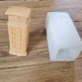 Silicone candle mold next to a finished orange telephone booth shaped wax candle - British Telephone Booth Style