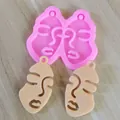 Close-up of pink abstract face silicone mold with two finished beige resin pendant samples - S