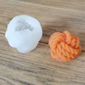 Detail view of a yarn ball silicone mold and finished orange aromatherapy candle. - Wool Ball Style (sku_645945529517)