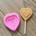 Detail view showing a pink heart silicone lollipop mold with a finished beige treat - Small Heart