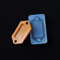 Dettaglio di uno stampo in silicone rettangolare e di una piastrina in resina arancio. - Stampo Etichetta Rettangolare Doppio Foro Rotondo (6#)