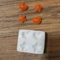 Detailansicht der Silikonform mit Herz- und Sternformen sowie orangefarbenen Mustern. - 4-Loch Stern Herz
