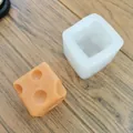 Detailed view of a square dice-shaped silicone mold alongside a finished cheese cube - White