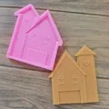 Détail montrant un moule en silicone rose en forme de maison et son biscuit terminé. - Château