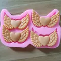 Close-up detail view of pink heart-wing silicone mold with finished chocolate samples - 4-in-a-row
