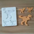 Molde de silicona con forma de dinosaurio con colgantes de resina naranja sobre fondo de madera - Estilo Dinosaurio