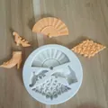 Detail view of a silicone mold with vintage fan and shoe patterns and orange molded pieces - Fan