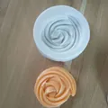 Draufsicht auf weiße Silikon-Backform und fertiges orangefarbenes Wirbelgebäck - Windbeutel-Spiralmuster (Stil 4) / 4