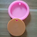 Detail view showing a round pink silicone mold alongside its orange circular cast piece - Small Round